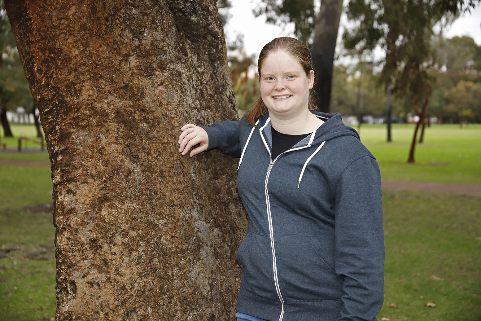 Young woman leaning on tree in park